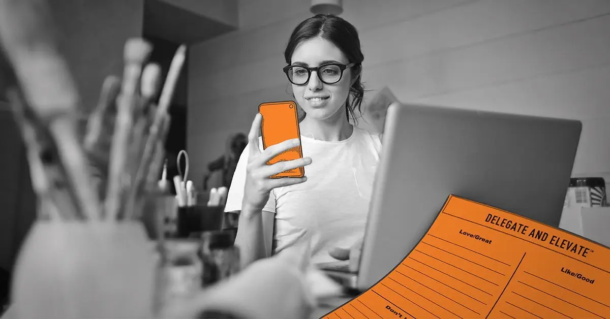 a woman holding a cell phone in front of a laptop computer